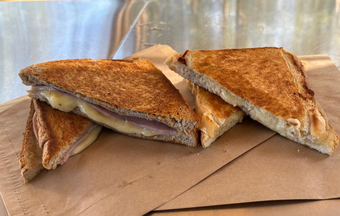 Golden ham and cheese jaffle toasties cut in halves on brown paper bags
