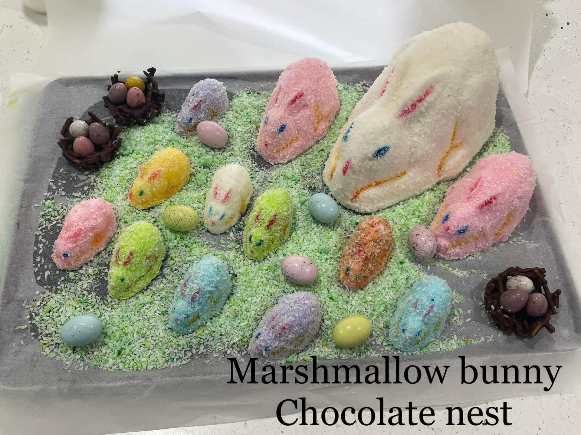 Handmade marshmallow Easter bunnies and chocolate nests with mini speckled eggs on green coconut grass